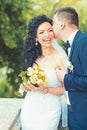 Groom kiss happy bride with bouquet. Woman and man smile on wedding day. Wedding couple in love. Newlywed couple on Royalty Free Stock Photo