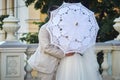 groom kisses the bride covered with a white lace umbrella. wedding scene on the balcony