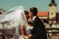 Groom kisses a bride dancing with her on the roof in a windy weather