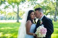 Groom kisses bride on her cheeks, Caucasian groom and Asian bride