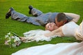 The groom kisses the bride lying on a grass Royalty Free Stock Photo