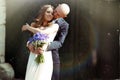 Groom kisses bride's cheek hugging her from behind in the rays o