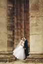 Groom kisses bride`s neck standing between the pillars Royalty Free Stock Photo