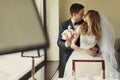 Groom kisses a bride standing behind a window Royalty Free Stock Photo