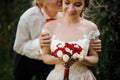 Groom kissing his young and beautiful bride in background of green tree Royalty Free Stock Photo