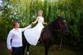 The groom leads the horse by the bridle. Bride sits in the saddl Royalty Free Stock Photo