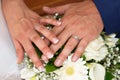 Groom man and bride woman fingers hands with wedding rings over marriage bouquet flowers Royalty Free Stock Photo