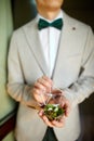 Groom men holding wedding rings lie on a beautiful, decorative hand made rustic box with plants inside, copy space, Royalty Free Stock Photo