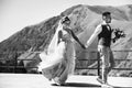Groom in modern suit and bride in charming pink dress pose on the terasse with great mountain view in Georgia Royalty Free Stock Photo