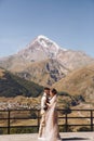 Groom in modern suit and bride in charming pink dress pose on the terasse with great mountain view in Georgia Royalty Free Stock Photo