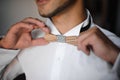Groom morning preparation. Bearded groom getting dressed in wedding shirt with wooden bow tie Royalty Free Stock Photo