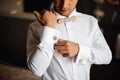 Groom morning preparation. Young groom getting dressed in a wedding shirt with wooden bow tie Royalty Free Stock Photo