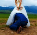 Groom peeking under his bride dress - funny wedding concept.