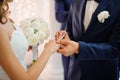 Groom puts on a gold wedding ring on the finger of a bride in a white dress Royalty Free Stock Photo