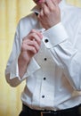 A groom putting on cuff-links as he gets dressed Royalty Free Stock Photo