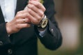 A groom putting on cuff-links as he gets dressed in formal wear. A man straightens cufflinks. Groom`s suit Royalty Free Stock Photo