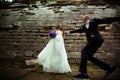 Groom runs to a bride while she waits for him behind a stone wall Royalty Free Stock Photo