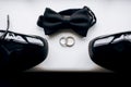 Groom\'s accessories in the form of black shoes, bow ties and wedding rings