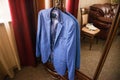 The groom`s blue jacket on a hanger on a vintage wardrobe. Groom`s morning, wedding details, preparation for the wedding ceremon Royalty Free Stock Photo