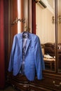 The groom`s blue jacket on a hanger on a vintage wardrobe. Groom`s morning, wedding details, preparation for the wedding ceremon Royalty Free Stock Photo