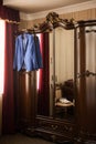 The groom`s blue jacket on a hanger on a vintage wardrobe. Groom`s morning, wedding details, preparation for the wedding ceremon Royalty Free Stock Photo