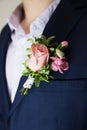 Groom`s boutonniere on a jacket of dark blue color. The wedding boutonniere consists of a pink rose, a small dianthus and a Royalty Free Stock Photo