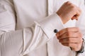 Groom`s morning. Wedding preparing. Man in white shirt putting on cufflinks. Business dress code Royalty Free Stock Photo