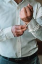 Groom`s morning. Wedding preparing. Man in white shirt putting on cufflinks. Business dress code