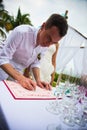 Groom signs documents on registration of marriage in the open air. A young couple signs the wedding documents. Man signs docum Royalty Free Stock Photo