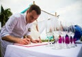 The groom signs documents on registration of marriage. A young couple signs the wedding documents. The man signs the documents