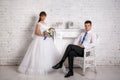 Groom is sitting in a chair and bride is standing near the fireplace Royalty Free Stock Photo