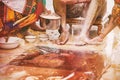 Family members pasting the turmeric powder haldi oil mixed with milk on groom`s feet and body