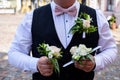 The groom, with a small bouquet of flowers attached to his waistcoat, holds two more bouquets