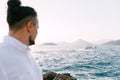 Groom stands on the rocks and looks at the motor yacht sailing on the sea Royalty Free Stock Photo