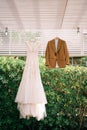 Groom suit and bride dress hang on hangers on a wooden canopy in the garden Royalty Free Stock Photo