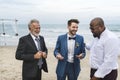 A groom talking to his groomsmen at the beach