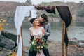 Groom tenderly embracing her beautiful bride by behind. Autumn wedding ceremony in rustic style outdoors. Happy Royalty Free Stock Photo