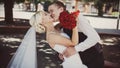 Kiss the bride and groom, the groom passionately hugs the bride on a wedding walk in the park