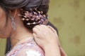 Groom wearing a necklace to the bride. mother of bride helping to dress up the necklace her beautiful daughter indoors . Bride