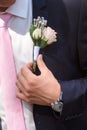 Groom wears boutonniere of roses on his jacket before the wedding ceremony