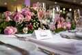 Groom wedding breakfast place setting with name card on top table waiting for arrival bride and pink roses and shiny glasses Royalty Free Stock Photo