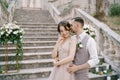Groom whispers in the bride ear while embracing her on the stone steps of an ancient villa Royalty Free Stock Photo