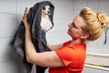 female groomer holds small dog in towel after washing wool in shower for further hair cutting