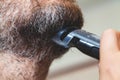 Grooming beard with gray hair trimmer closeup Royalty Free Stock Photo