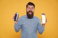 Grooming at every opportunity. Bearded man hold shampoo bottles yellow background. Cosmetics and toiletries. Hygiene and Royalty Free Stock Photo