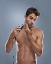 Grooming for the modern man. Studio portrait of a handsome young man shaving with an electric razor.