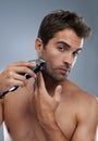 Grooming for the modern man. Studio portrait of a handsome young man shaving with an electric razor. Royalty Free Stock Photo