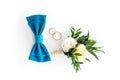 Grooms accessories. Blue bow tie, wedding golden rings and flower boutonniere on isolated white background. Royalty Free Stock Photo