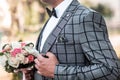 Grooms morning preparation, handsome groom getting dressed and preparing for the wedding, in gray suit in a cell with a brooch