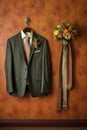 grooms suit, tie, and boutonniere hanging neatly